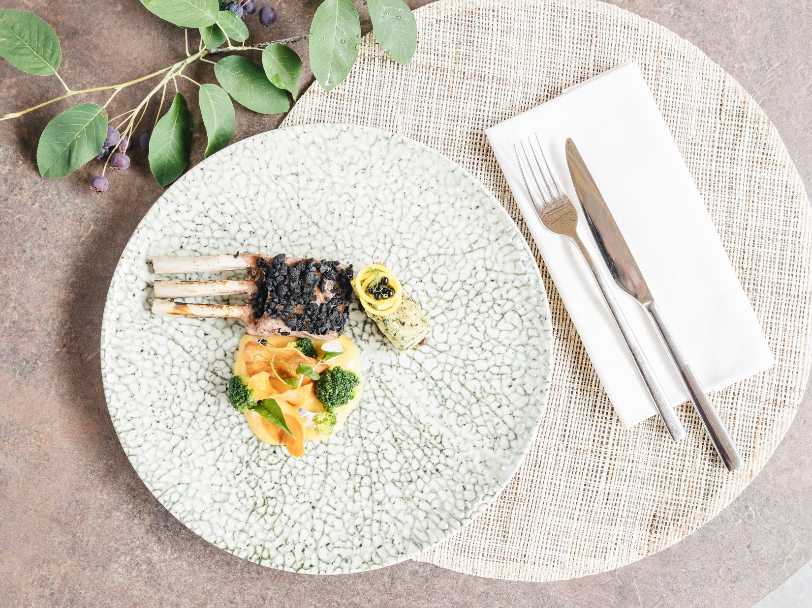 Sensoria Dolomites: hotel in montagna Piatto gourmet con costolette di agnello, verdure e posate decorative