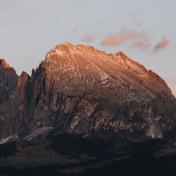 Romantic short break for couples – Sensoria Dolomites Alpine peak at sunset with light snow cover and forest in the foreground