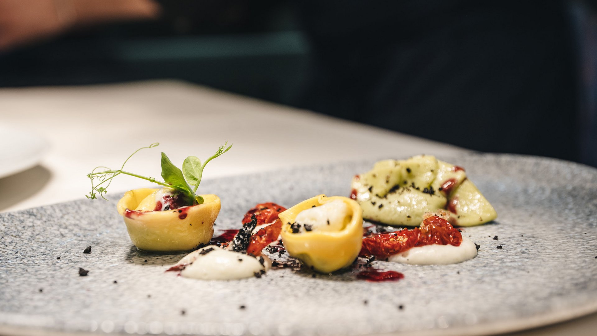Places of energy, divine flavours: Anima restaurant Finely plated Italian pasta with tomatoes and cream on a gray plate