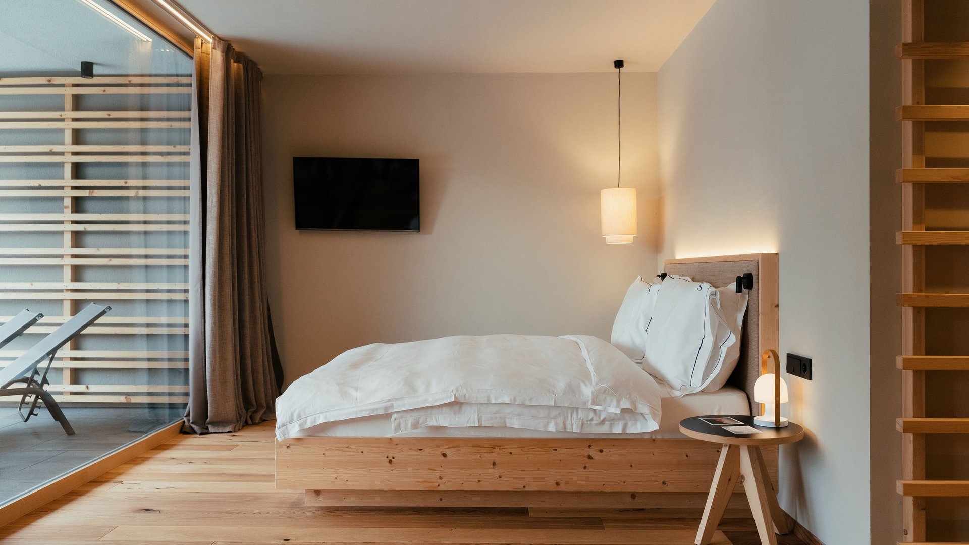 Sustainability at Sensoria Dolomites Modern bedroom with wooden details, double bed, and large window to the terrace