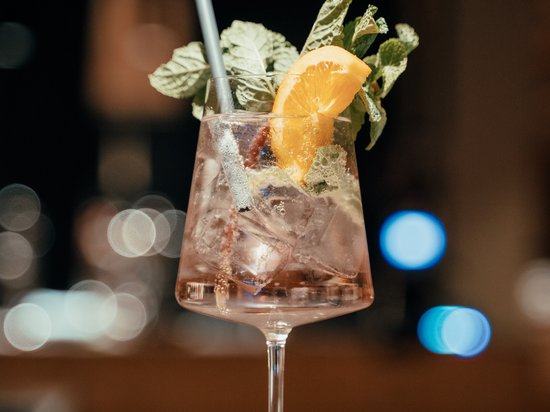 Ein Helikopterflug in den Dolomiten – Augenblicke über den Gipfeln Cocktailglas mit Eis, Minze, Orangenscheibe und Strohhalm