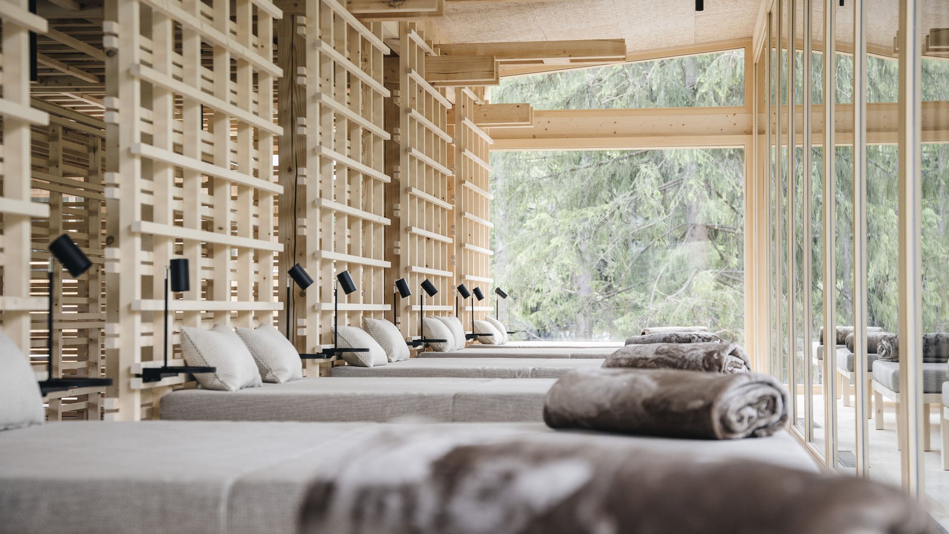 Wellness Aphrodite: Sensoria Dolomites among the winners Relaxation room with loungers, pillows, and large windows overlooking trees