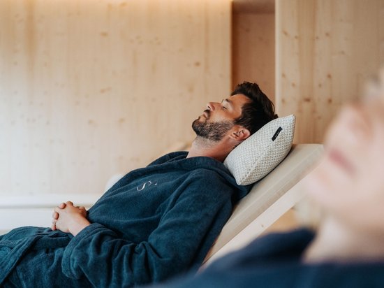Sensoria Dolomites: Babymoon in Südtirol Mann entspannt auf Liegestuhl mit geschlossen Augen und Kissen im Spa