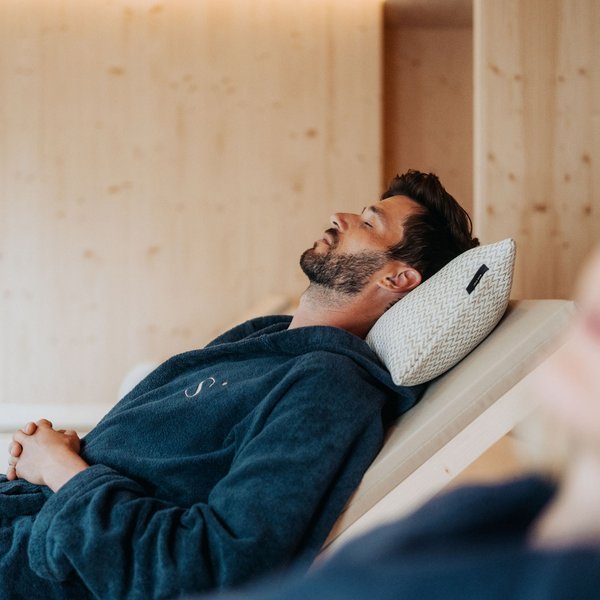 Sensoria Dolomites: Flitterwochen in Südtirol Mann entspannt auf Liegestuhl mit geschlossen Augen und Kissen im Spa