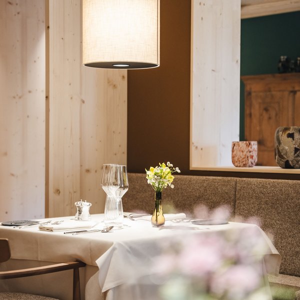 Genussurlaub in Südtirol – Sensoria Dolomites Gemütlicher Restauranttisch mit weißer Tischdecke und Blumenvase