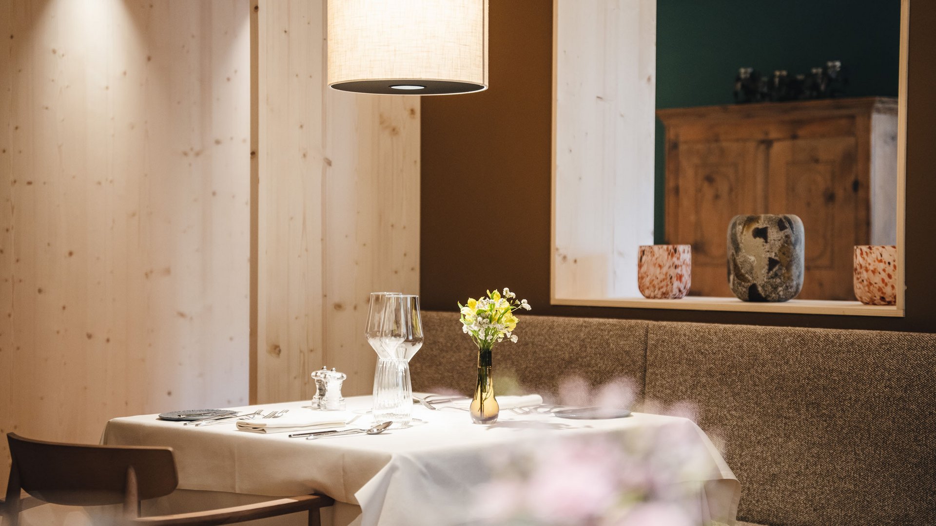 South Tyrolean recipes. Reinterpreted. Cozy restaurant table with white tablecloth and flower vase