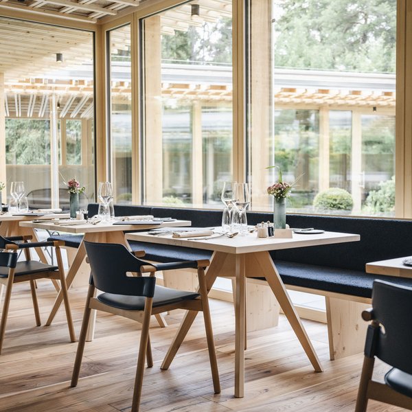 Sensoria Dolomites: Babymoon in Südtirol Modernes Restaurant mit Holzmöbeln und großen Fenstern mit Gartenblick