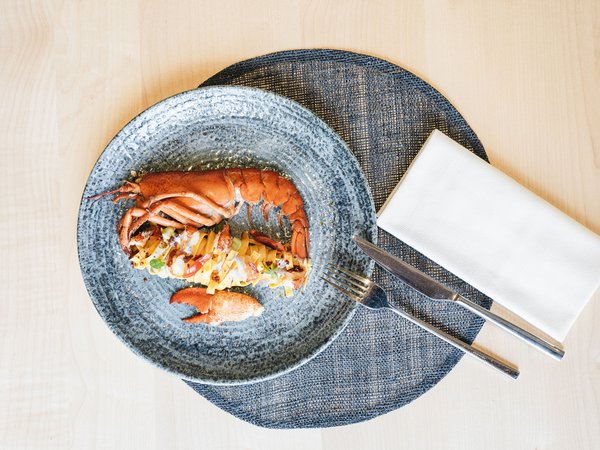 Wellness Aphrodite: Sensoria Dolomites among the winners Gourmet lobster dish on blue plate with cutlery and napkin
