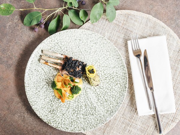 Wellness Aphrodite: Sensoria Dolomites among the winners Gourmet dish with lamb chops, vegetables, and sauce on decorative plate