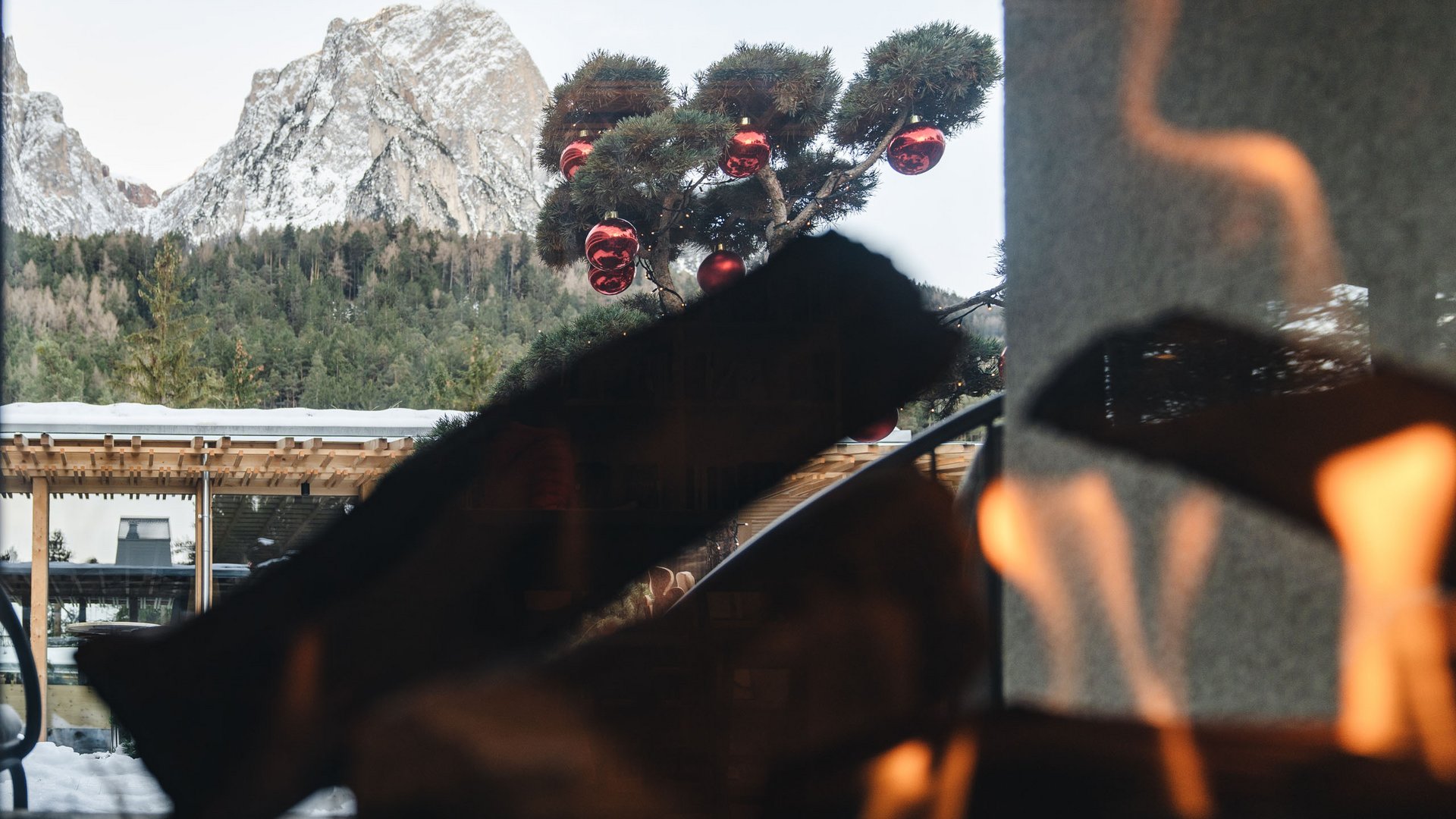 Kostbare Augenblicke in Ihrem Romantikhotel in den Dolomiten Blick auf schneebedeckte Berge und Tannenzweig mit roten Weihnachtskugeln