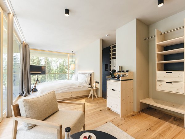 Wellness Aphrodite: Sensoria Dolomites among the winners Modern hotel room with wood floor and large window overlooking forest