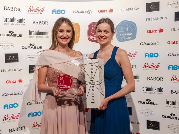 Wellness Aphrodite: Sensoria Dolomites among the winners Two women holding an award and gift in front of sponsor backdrop