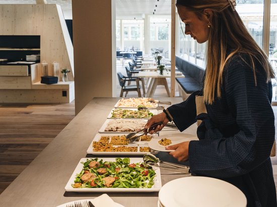 Unser Genussmarkt – perfekt für Ihr Romantikwochenende Frau nimmt Essen vom Buffet in modernem Restaurant