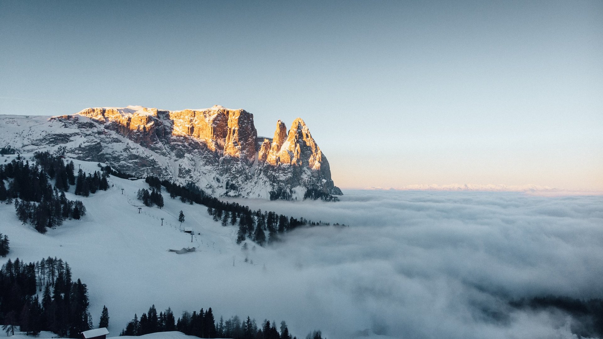 A magical holiday in the Dolomites at New Year Snowy mountains at sunset with fog in the valley