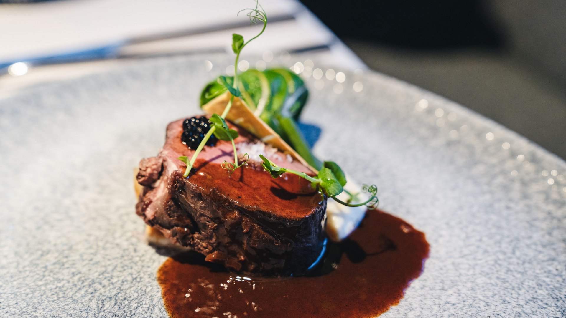 Sustainability at Sensoria Dolomites Gourmet beef filet with sauce and green vegetable garnish on plate