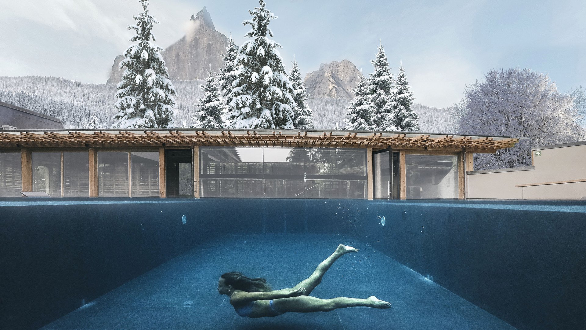 Von Wanderungen auf der Seiser Alm in die Spa Area Frau schwimmt unter Wasser im Pool mit schneebedeckten Bäumen und Bergen im Hintergrund