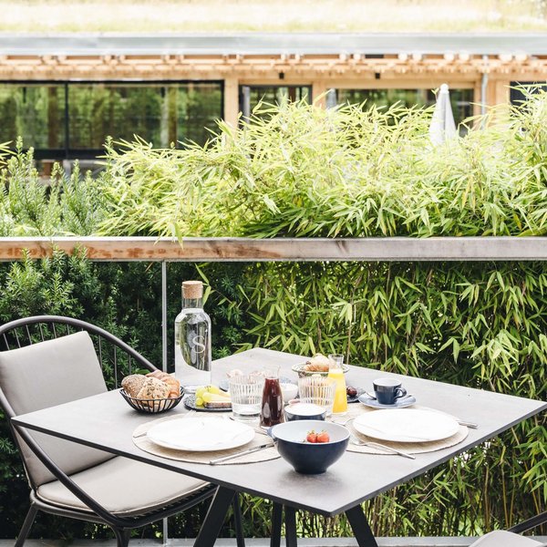 Sustainability at Sensoria Dolomites Table with breakfast outdoors on terrace with green plants