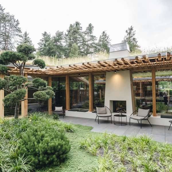Sensoria Dolomites: Babymoon in Südtirol Moderner Garten mit Terrasse, Kamin und Holzpergola umgeben von Bäumen