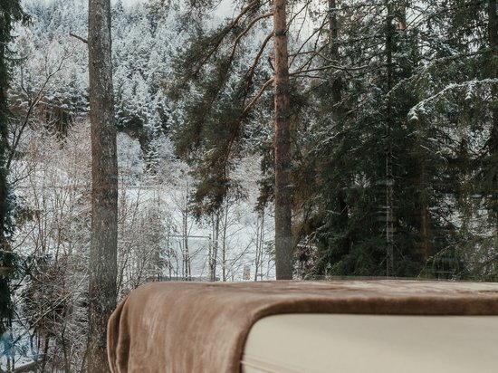 Wellness on Alpe di Siusi/Seiser Alm – Sensoria Dolomites Massage table with blanket by panoramic window overlooking snowy forest