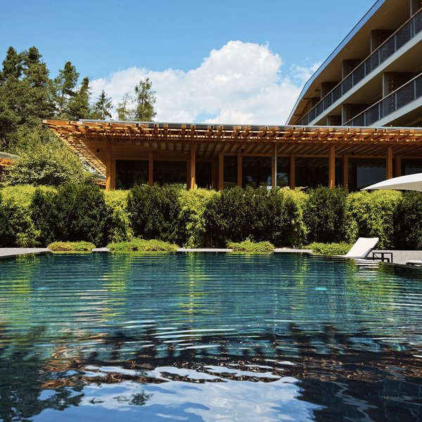 From hiking on Alpe di Siusi/Seiser Alm to the spa area Outdoor pool with lounge chair and modern building on a sunny day