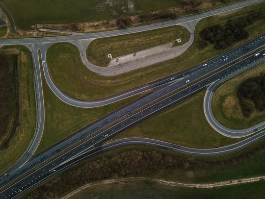 How to reach your getaway on Alpe di Siusi in South Tyrol Aerial view of highway with winding ramps and light traffic