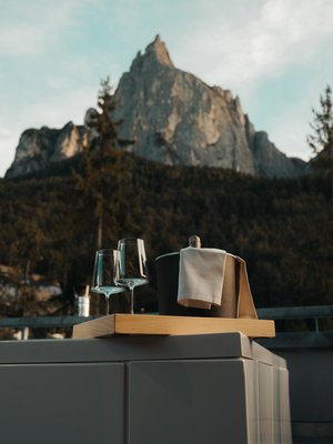 Luxus für die Seele im Kurzurlaub in Südtirol Weingläser und ein Eiskübel auf einem Tisch mit Berg im Hintergrund