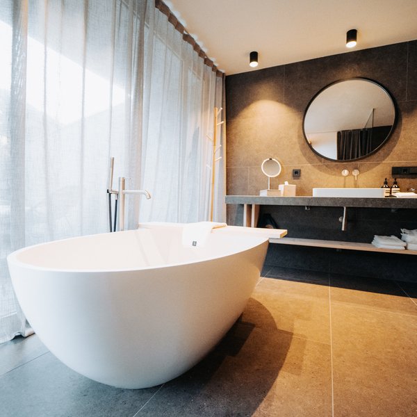 Sensoria: Private Spa Suite mit Whirlpool in Südtirol Modernes Badezimmer mit freistehender Badewanne und großem rundem Spiegel