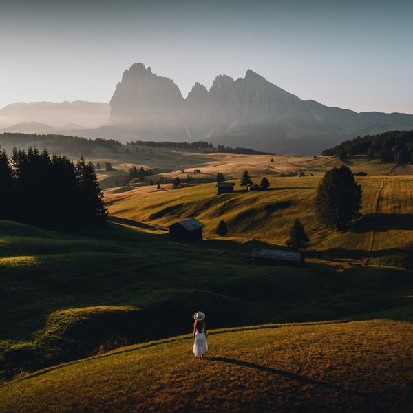 Romantischer Kurzurlaub für Verliebte – Sensoria Dolomites Frau im weißen Kleid auf einer Wiese mit Bergpanorama im Hintergrund