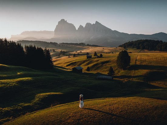 Hotel a Siusi allo Sciliar? Sensoria Dolomites! Donna in abito bianco su prato con vista sulle montagne sullo sfondo
