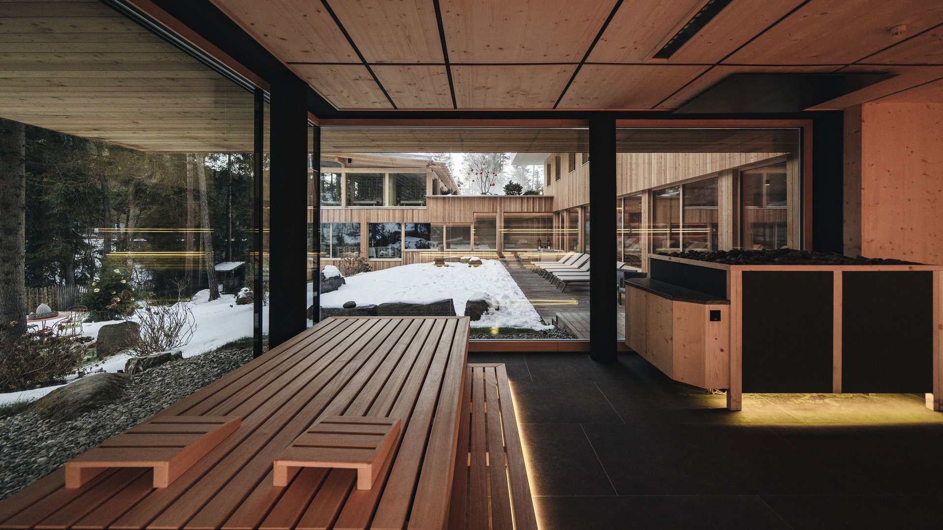 Hotel all’Alpe di Siusi: un tempio di energia per l’anima Sauna moderna con ampie finestre e vista su giardino innevato