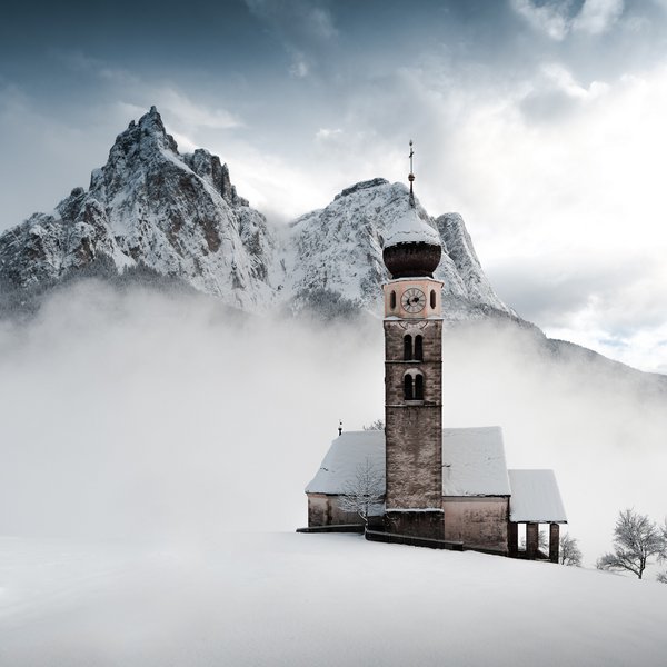 Active holidays in South Tyrol – ready for pure nature? old church in snow with fog and snowy mountains in background