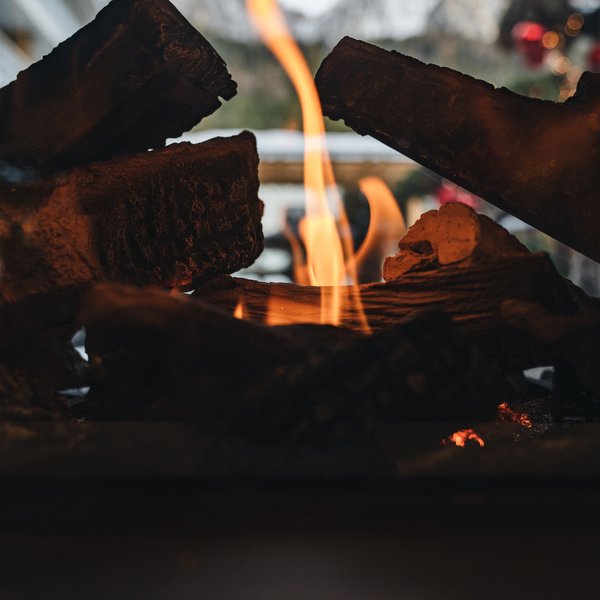 Sensoria Dolomites: il vostro hotel sull’Alpe di Siusi Fiamme in un camino a legna con montagne sullo sfondo