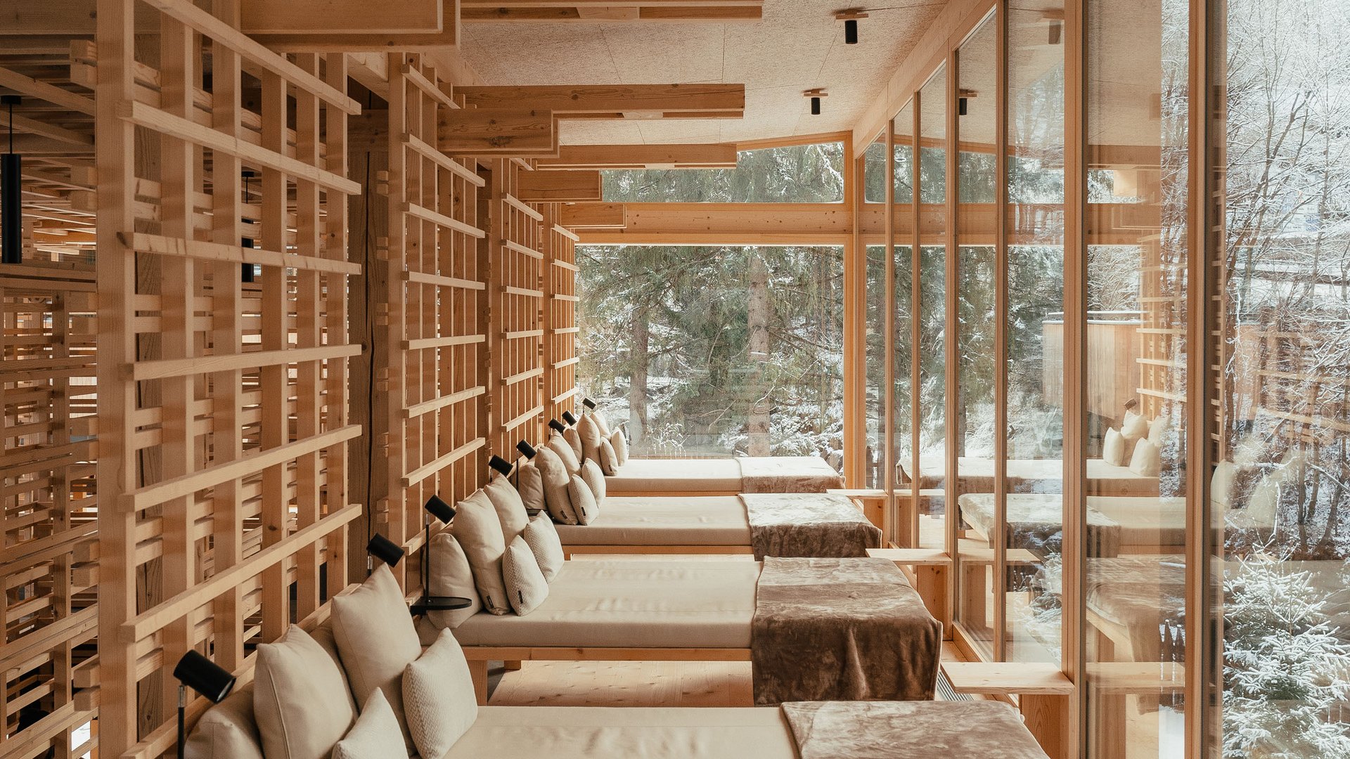 Wellness Aphrodite: Sensoria Dolomites tra i vincitori Lettini in legno chiaro con cuscini in una stanza con ampie finestre e vista invernale