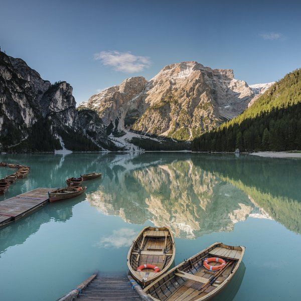 Sensoria Dolomites: much more than a hotel in South Tyrol Boats on clear blue mountain lake with mountain and forest reflections