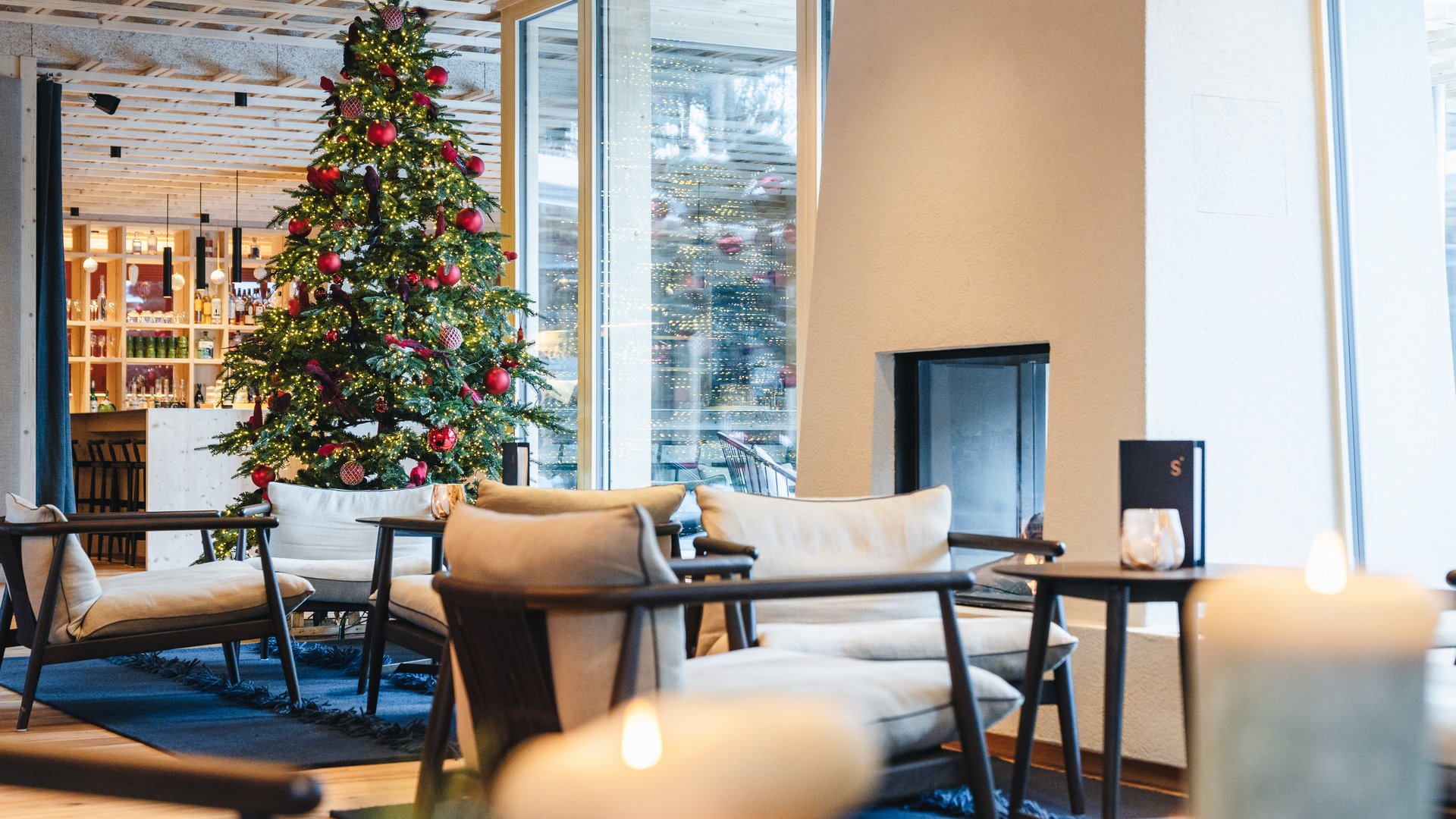 Sensoria Dolomites: il vostro hotel sull’Alpe di Siusi Albero di Natale decorato in una moderna lounge con poltrone e ampie finestre
