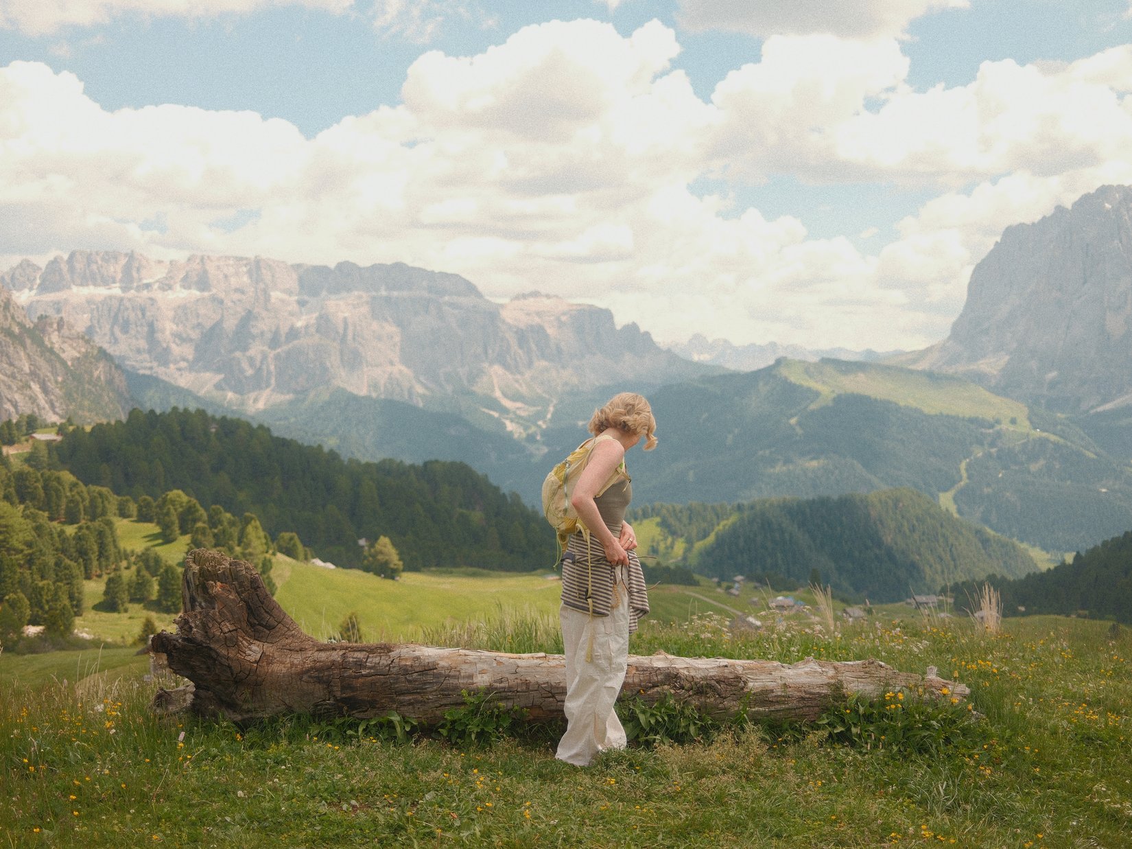Offers – holidays in the Dolomites UNESCO World Heritage Woman with backpack standing on grassy field with mountain view and tree log