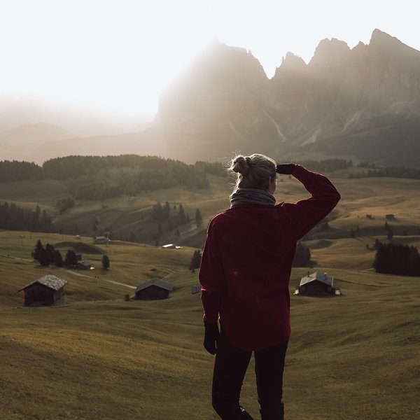 Active holidays in South Tyrol – ready for pure nature? Person looking at mountains at sunrise on a green meadow