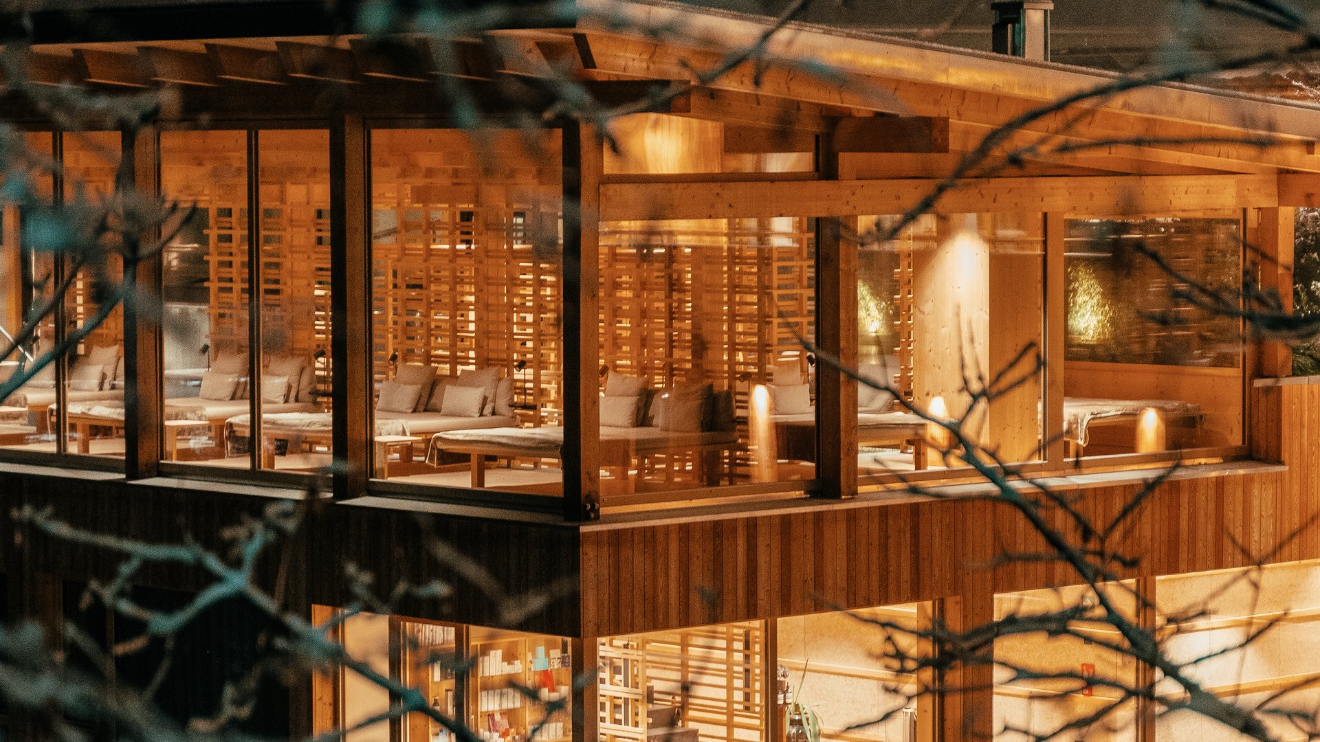 Hotel all’Alpe di Siusi con piscina: lusso per l’anima Casa in legno moderna di notte con interni illuminati in una foresta innevata