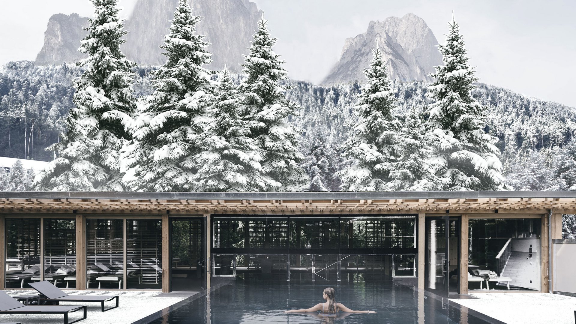 Das Badehaus im Hotel mit Pool in den Dolomiten Frau schwimmt im Pool mit verschneiten Tannen und Bergen im Hintergrund