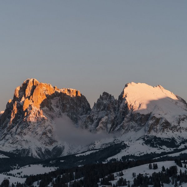 Settimana bianca sulle Dolomiti, al Sensoria Dolomites Montagne innevate illuminate dal tramonto con riflessi arancioni