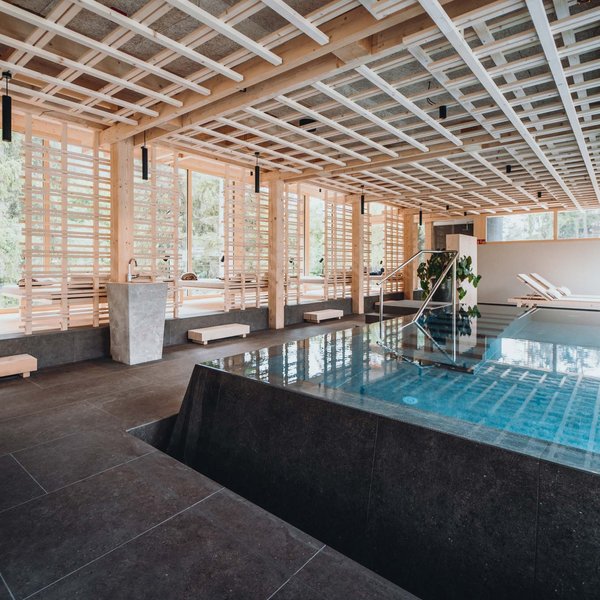 Sensoria Dolomites: Wellnesshotel in den Dolomiten Moderner Innenpool mit Holzdecke und Liegestühlen neben großen Fenstern