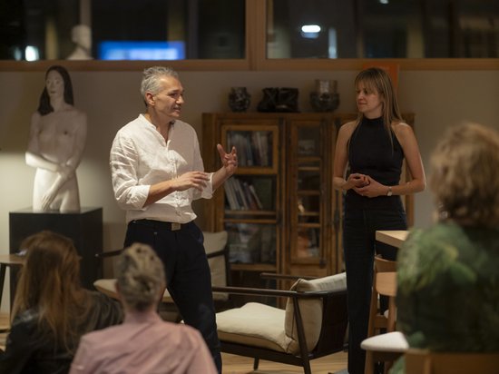 Sensoria Art Edition Zwei Menschen im Gespräch vor einer Gruppe in einem modernen Raum mit Skulptur.