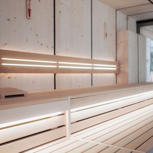 Hotel in mezzo alla natura: area spa del Sensoria Dolomites Interno di una sauna moderna con legno e illuminazione indiretta