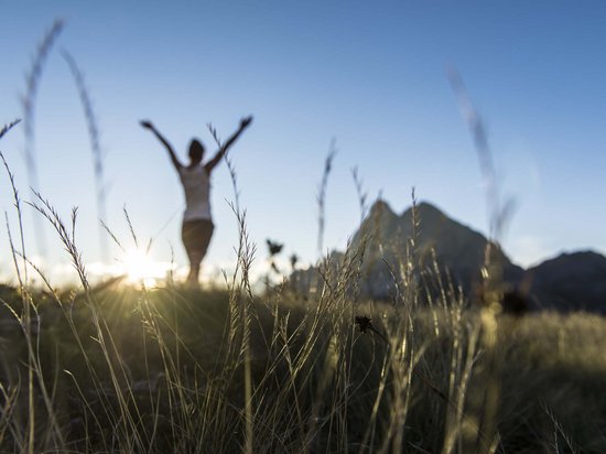Alpe di Siusi/Seiser Alm Balance – in harmony with nature Person with arms raised in mountain meadow at sunset