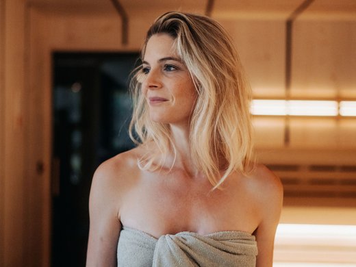 A day spa in the Dolomites to soothe your soul Woman wrapped in towel inside wooden sauna room