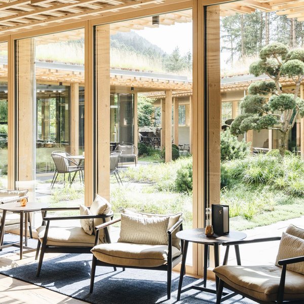 Sustainability at Sensoria Dolomites Bright lounge room with large windows overlooking a garden with trees