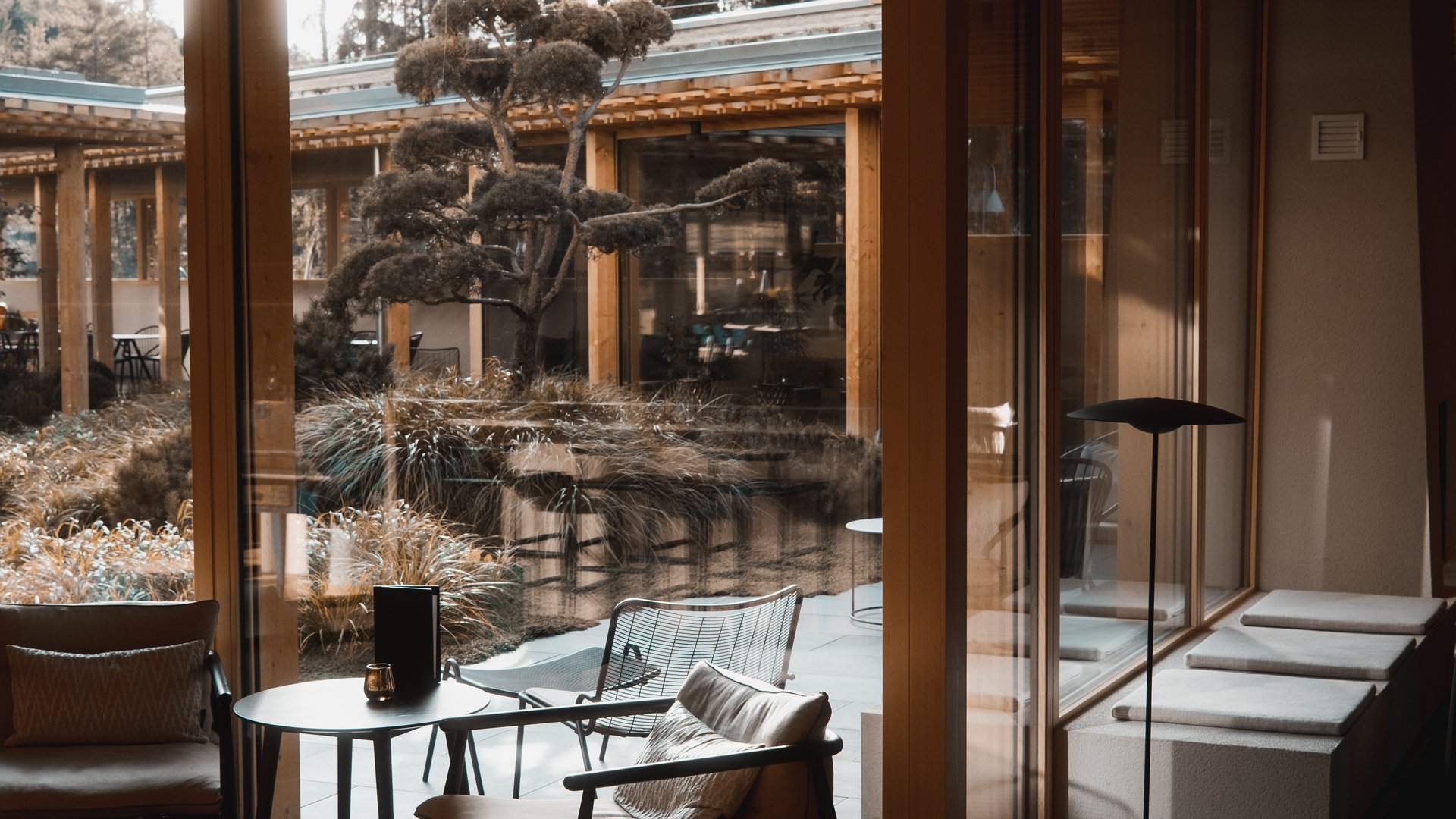 Hotel all’Alpe di Siusi: un tempio di energia per l’anima Area salotto accogliente con sedie e tavolo davanti a grandi finestre con vista sul giardino