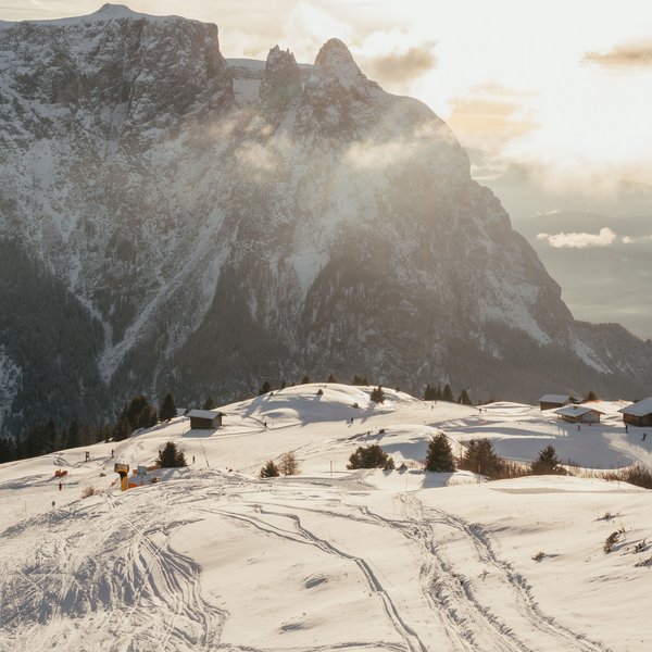 Settimana bianca sulle Dolomiti, al Sensoria Dolomites Paesaggio montano innevato con tracce di sci e sole al tramonto sullo sfondo