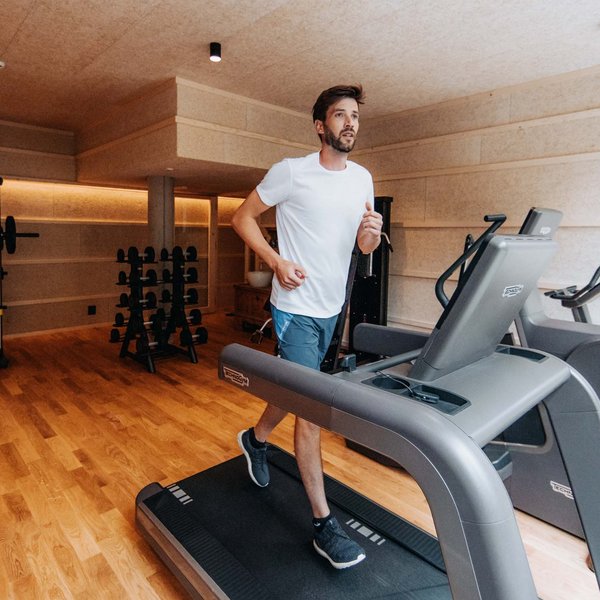 Sensoria Dolomites: Wellnesshotel in den Dolomiten Mann läuft auf Laufband in modernem Fitnessstudio