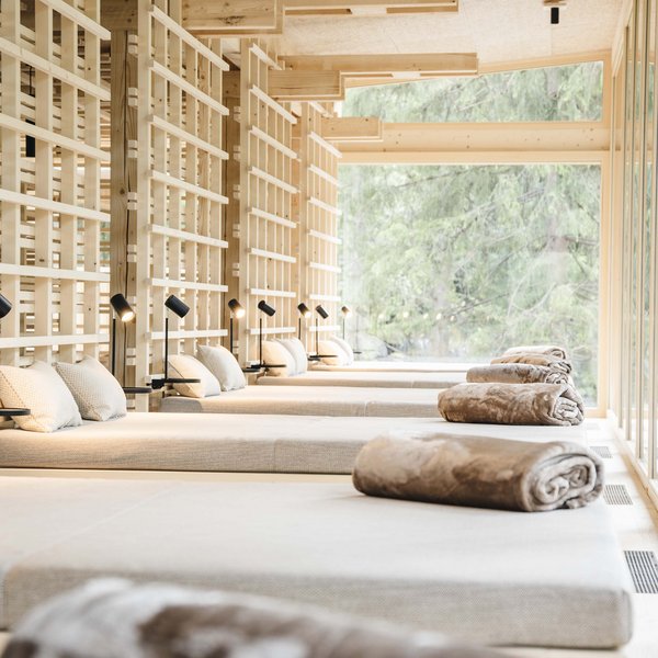 Sensoria Dolomites: Wellnesshotel in den Dolomiten Moderne Entspannungsliegen mit Kissen und Decken in hellem Spa-Raum mit Blick nach draußen